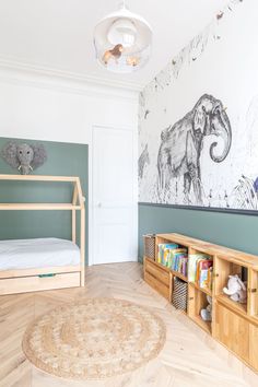 a room with a bed, bookcases and an elephant painting on the wall