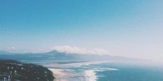 an aerial view of the ocean and beach from a high point of view on a sunny day