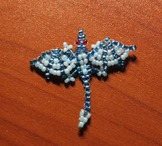 a beaded dragon brooch sitting on top of a wooden table