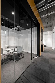 an empty office with glass walls and white tables in the center, surrounded by chairs