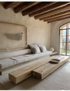 a large wooden bench sitting in the middle of a living room next to a window