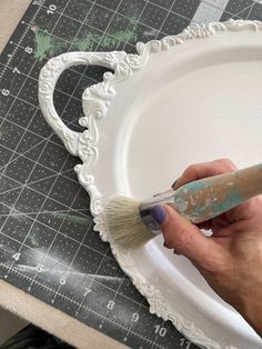 a person using a paintbrush on a white plate