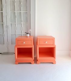 two orange nightstands sitting next to each other in front of a white wall and door