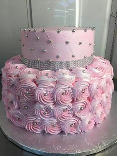 a pink cake with white frosting flowers and a tiara on top is sitting on a silver platter