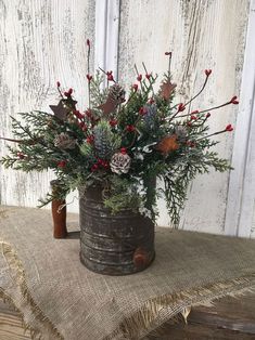 a wooden bucket filled with red berries and greenery on top of a burlock