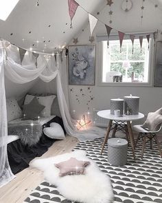 a room with white curtains and black and white flooring, some lights strung from the ceiling