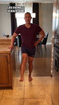 a man standing in the middle of a kitchen with his legs crossed and feet on the counter