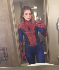 a woman taking a selfie in a bathroom mirror wearing a spider - man costume