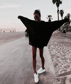 a woman is standing on the beach with her arms spread out in front of her