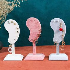 three different shaped jewelry stands sitting on a table next to a vase with flowers in it