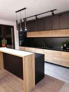 an empty kitchen with black counter tops and wooden cabinetry, along with potted plants