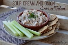 a bowl of chicken salad with celery and crackers on a white plate