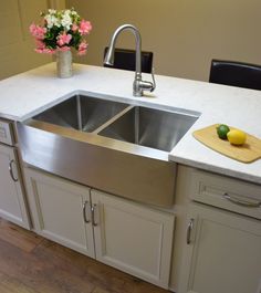 a stainless steel sink in a kitchen with flowers on the counter top and a cutting board