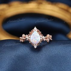 an opal and diamond ring on top of a blue cloth