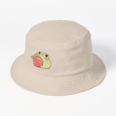 This packable, scrunchable, lightweight headwear classic is ready for adventure, from the beach to the street to the trail Breathable 100% cotton with eyelet ventilation Flat top Moderate brim is 2.2"" (5.5 cm) wide to keep the sun off your face Unstructured crown is 3.1"" (8 cm) deep Easy care: just spot clean and dry in shade. Cute frog holding a strawberry Frog With Strawberry, Strawberry Bucket Hat, Cute Frog, Cute Frogs, Hats For Sale, Flats Top, The Trail, Bucket Hat, Crown