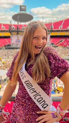 a beautiful young woman standing in front of a stadium