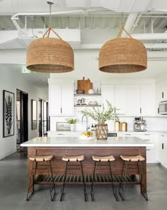 an open kitchen with two hanging baskets over the island