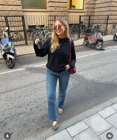 a woman is walking down the street with her hand up in the air and smiling