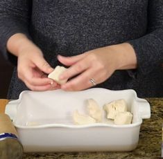 a woman is preparing food in a white dish