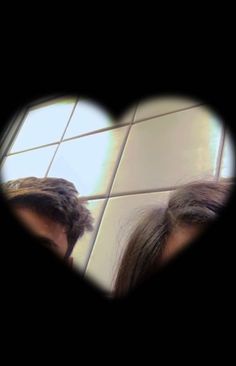 the reflection of two people in a heart - shaped mirror, with one person looking at their hair