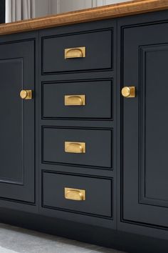 a black cabinet with gold handles and knobs on the doors is seen in this image