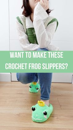 a woman sitting on the floor with her legs crossed and wearing crochet frog slippers