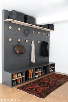 a coat rack with shoes and purses hanging on the wall next to a rug