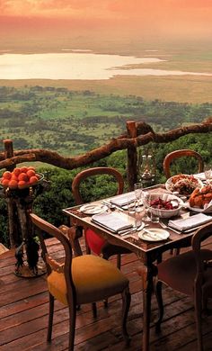 an outdoor dining table with food on it overlooking the water and land in the distance