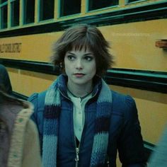 a woman standing in front of a school bus with her hand on her hip and looking at the camera