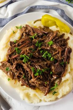 a white plate topped with mashed potatoes covered in beef and garnished with parsley