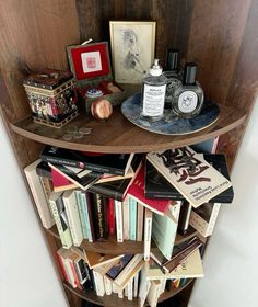 a bookshelf filled with lots of books on top of a wooden shelf next to a wall