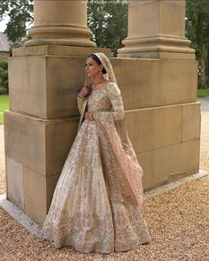 a woman in a wedding dress leaning against a pillar