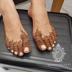 the feet are decorated with henna on top of a mat in front of a woman's legs