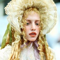 a close up of a doll with blonde hair and a big hat on her head