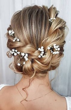 the back of a woman's head with flowers in her hair, wearing a white dress