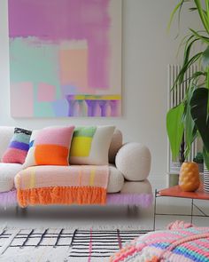 a living room filled with furniture and a large colorful painting on the wall behind it