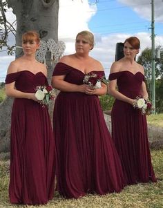 three bridesmaids standing in front of a grave with their dresses pulled back and flowers in their hair