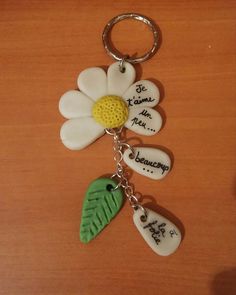 a keychain with three flowers and two words written on the front, one has a green leaf attached to it