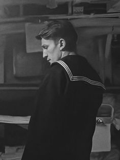 black and white photograph of young boy in sailor's uniform looking down at papers