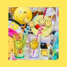 two glasses with smiley faces on them and straws sticking out of the top one