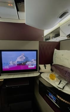 a flat screen tv sitting on top of a wooden desk next to a window in an airplane