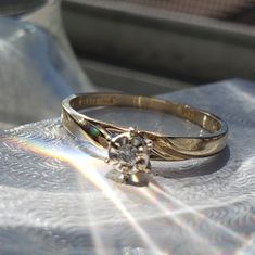 a diamond ring sitting on top of a piece of paper next to a glass bottle