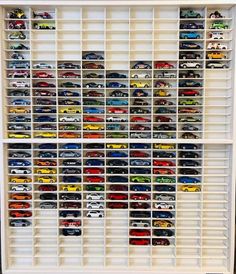 a white shelf filled with lots of toy cars on top of it's sides