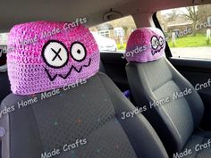 two crocheted hats sitting on the back seat of a car with eyes and nose