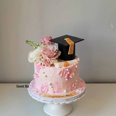 a pink and white cake with a graduation cap on top that is decorated with flowers