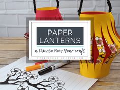 two paper lanterns sitting on top of a table next to some crayon pens