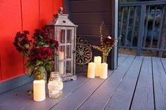 some candles are sitting on a wooden table with flowers and a lantern next to it