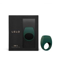 a green ring sitting in front of a black box next to it's packaging