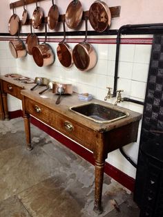 an old fashioned kitchen with pots and pans hanging on the wall above the sink