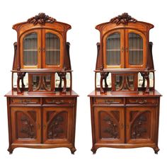 two wooden china cabinets sitting side by side